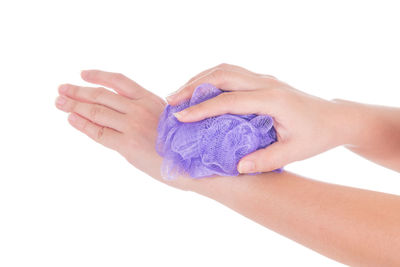 Cropped hand holding bath sponge against white background