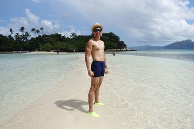 Full length of shirtless man standing at beach