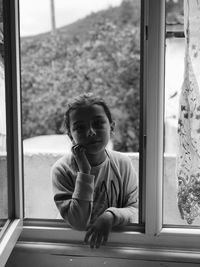 Portrait of girl looking through window
