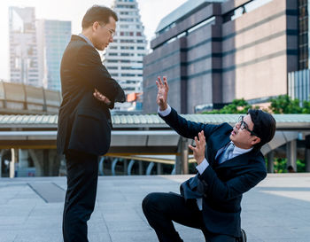 Businessman scolding colleague on city street against building