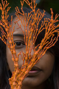 Close-up portrait of a young woman with  orange seaweed 