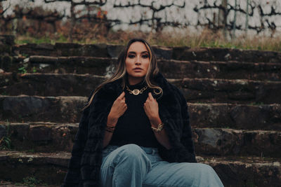 Portrait of beautiful young woman sitting on staircase