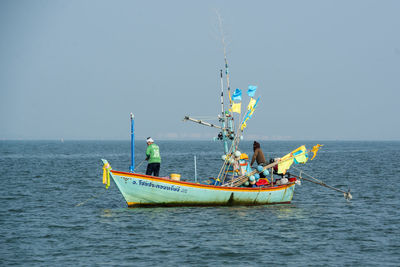 Fishing boat in sea against clear sky