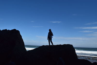 Full length of man standing on rock at beach against sky