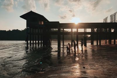 Silhouette people on pier against sky during sunset