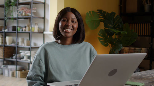 Portrait of young woman using laptop at home