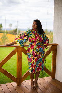 Portrait of young woman standing against railing