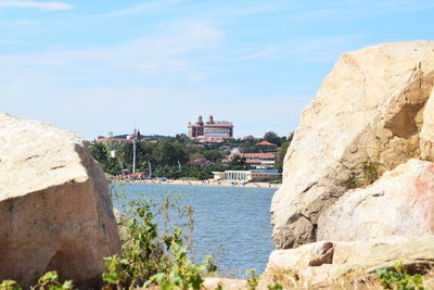 Rock formations by sea against sky in city