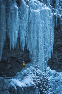 Woman by icicles in cave