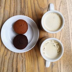 Directly above shot of cupcakes and coffee cups on table