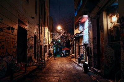 Narrow alley amidst buildings in city at night