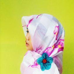 Side view of girl wearing hijab against yellow background