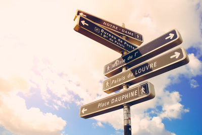 Low angle view of sign board against cloudy sky