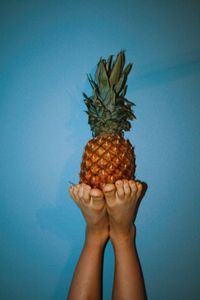 Midsection of person holding fruit against blue background