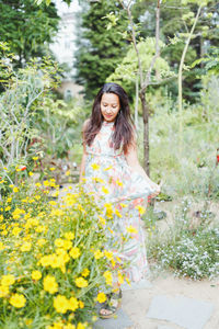 Happy multiracial japanese woman in maxi dress and wedge heels, summer garden