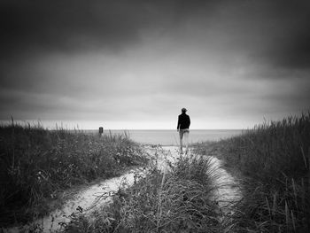 Rear view full length of woman walking at beach against sky