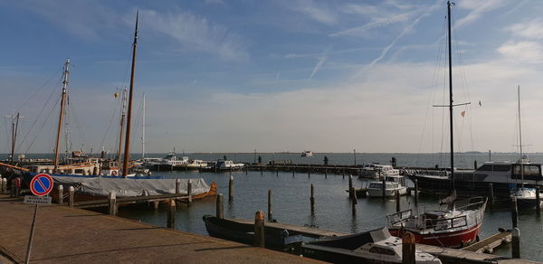 Boats moored at harbor against sky