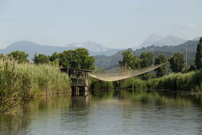 Scenic view of lake and mountains against sky and fishing still house with net