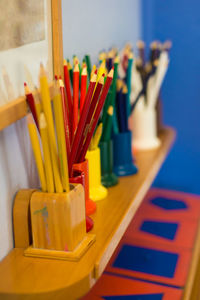 Colorful pencils in desk organizers on shelf