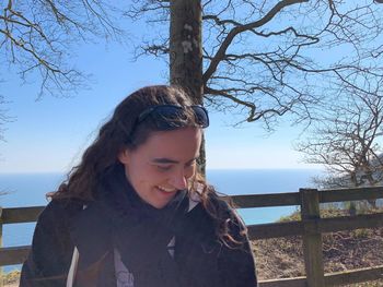 Young woman smiling by sea against sky