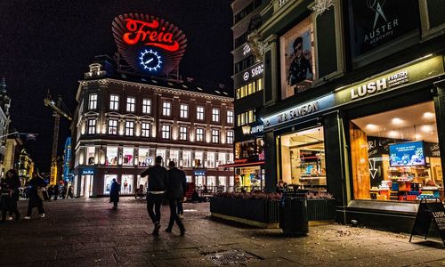 People walking on illuminated street at night