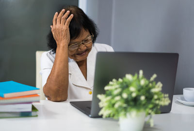 Smiling senior woman using laptop in office