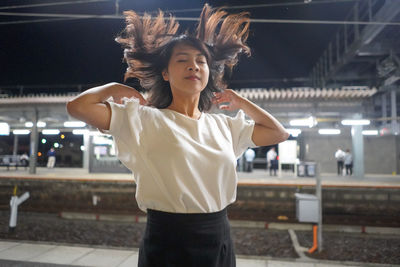 Young woman tossing her hair while standing at railway station platform 