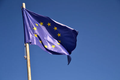 Low angle view of flag against blue sky