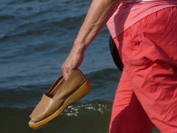 Midsection of man holding while standing by sea