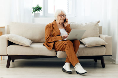 Young woman using laptop while sitting on sofa at home