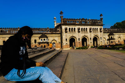 Man in front of historical building against blue sky