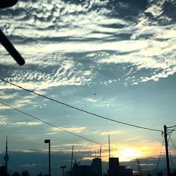 Low angle view of power lines against cloudy sky