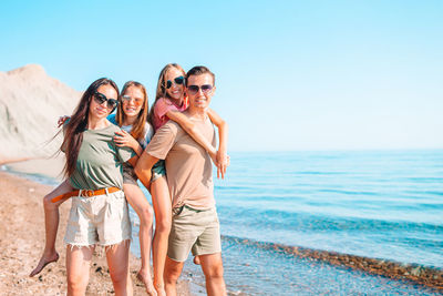 Portrait of friends at beach against sky