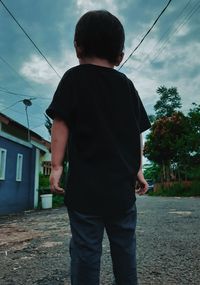 Rear view of man standing against building in city