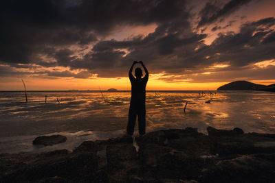 Silhouette man standing on beach during sunset