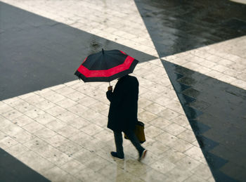 Rear view of woman walking with umbrella