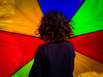 Rear view of woman standing on multi colored umbrella