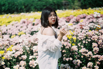 Young woman standing by flowering plants