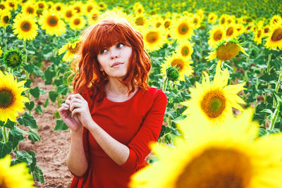 Smiling young woman with yellow flowers in field