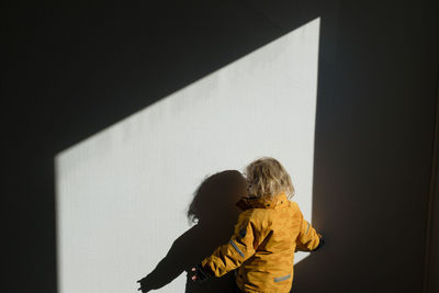 Rear view of two women standing against wall