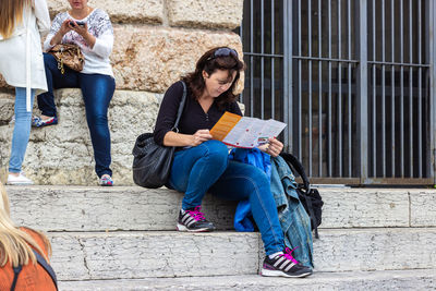 Full length of woman sitting on staircase in city