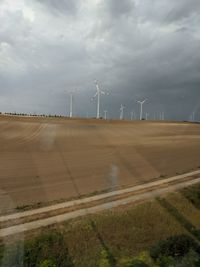 Wind turbines on field against sky