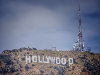 Low angle view of telephone booth against sky and the hollywood sign