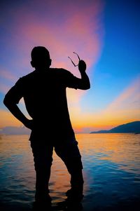 Silhouette man standing on beach against sky during sunset