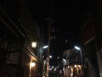 Illuminated street light in city against sky at night