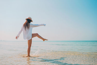 Woman splashing water on beach