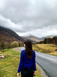 Rear view of woman standing on road against sky