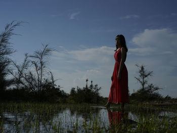 Woman standing by lake against sky