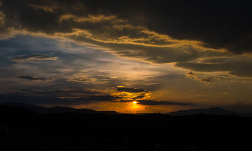 Scenic view of silhouette mountains against dramatic sky