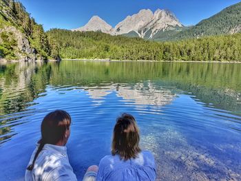 Rear view of woman looking at lake against mountain